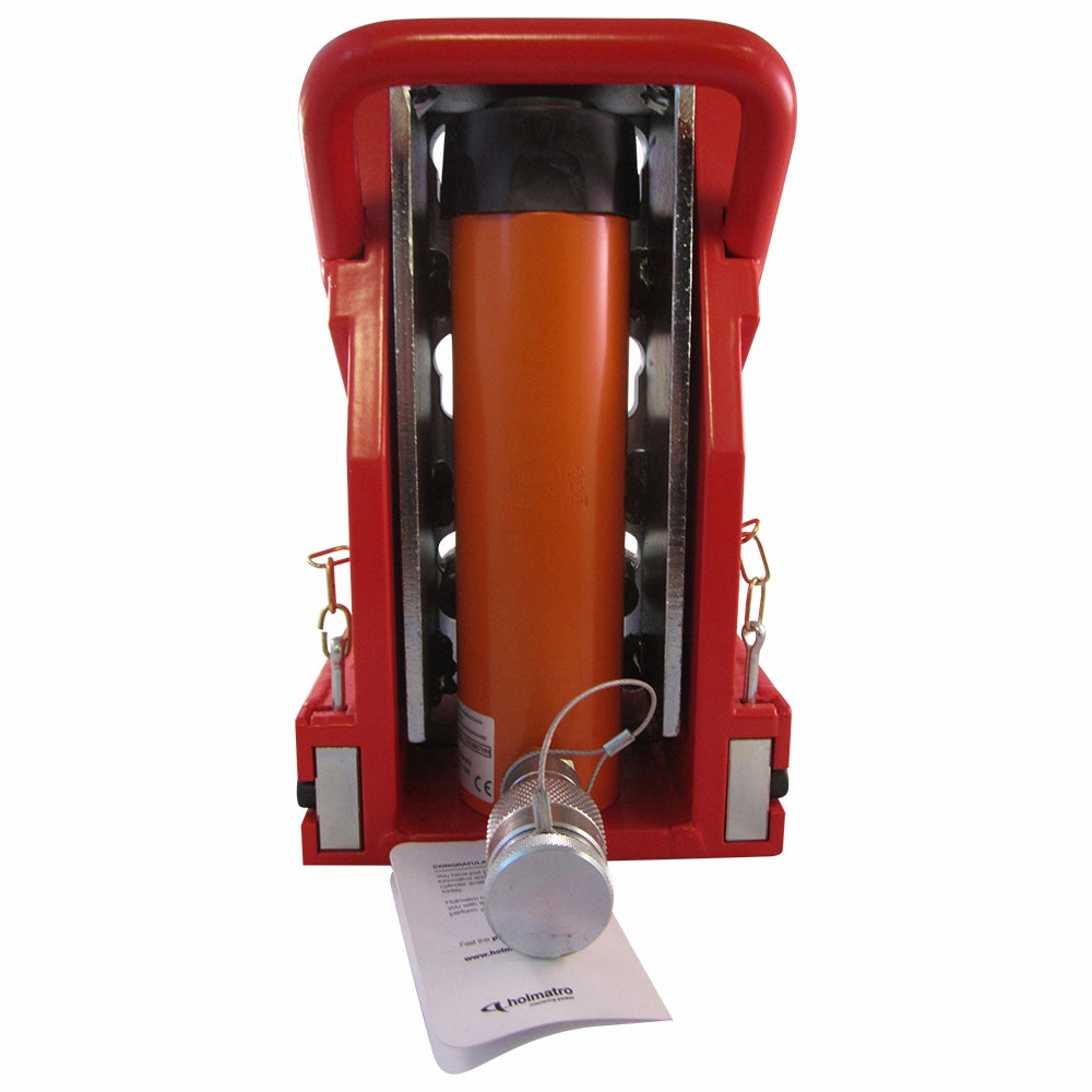 Rød hydraulisk donkraft med orange cylinder og sølvkomponenter. Dokumenter ligger under cylinderen.
