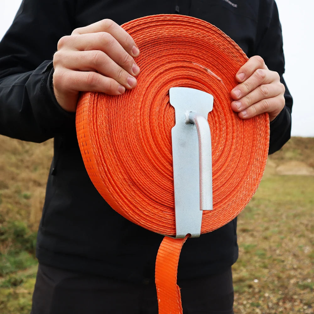 Person holder en orange rullebånd med Dynello båndopruller, der har en cylinder og krogform.