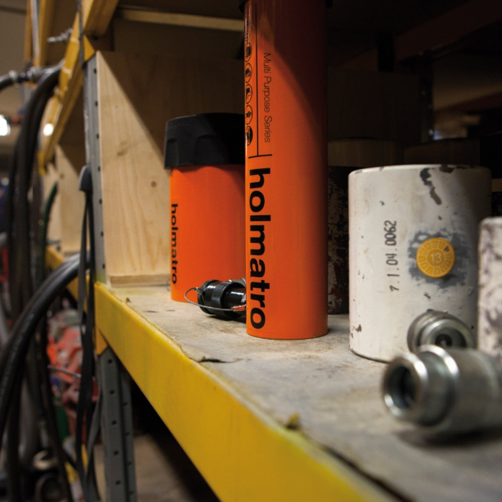Orange Holmatro cylinder på hylde med værktøj. "Multi Purpose Series" synlig på siden.