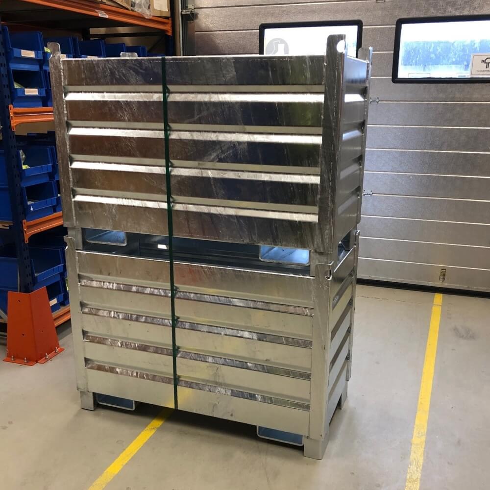 Stor metalopbevaringskasse med vandrette lameller og forstærkede hjørner i industrielt miljø.