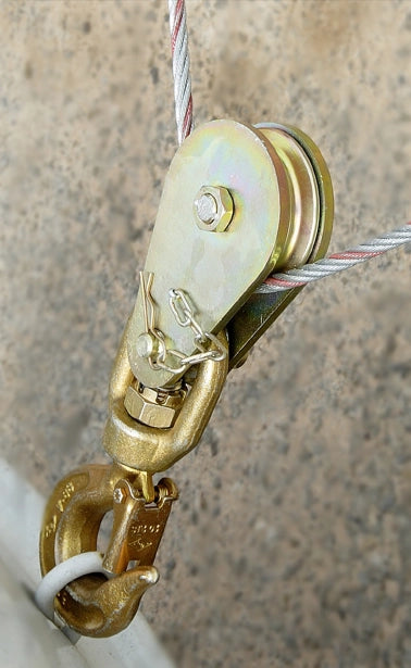 Kasteblok med krog og kabel, fastgjort til overflade. Rundt dæksel og robust design.