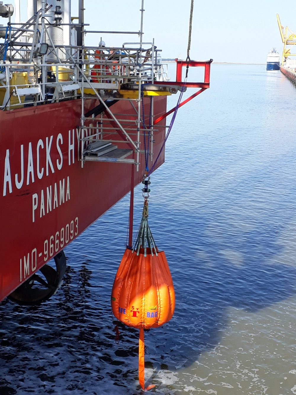 Orange SafetMade Waterbag "SAFE T BAG" 5T hænger fra skib over vand.