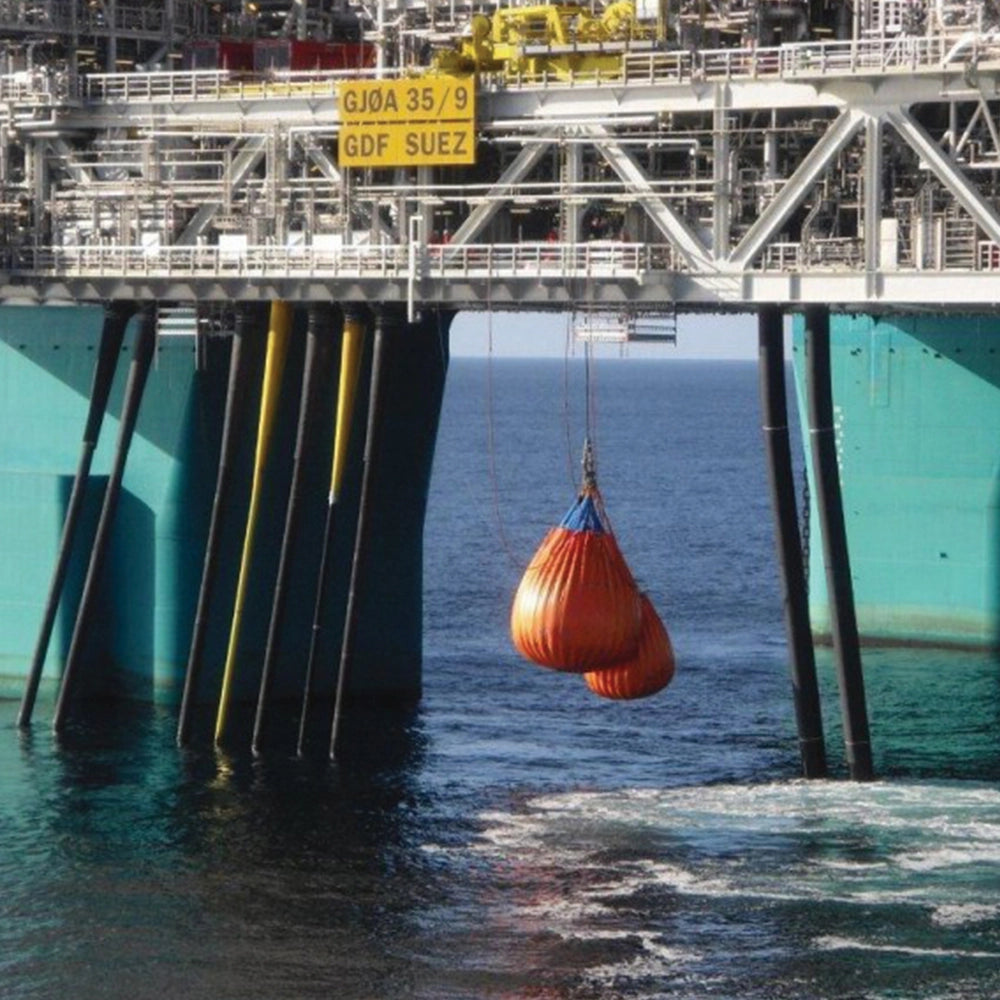 Orange vandpose under platform, markeret "SAFE T BAG" og "2T", i maritime omgivelser.